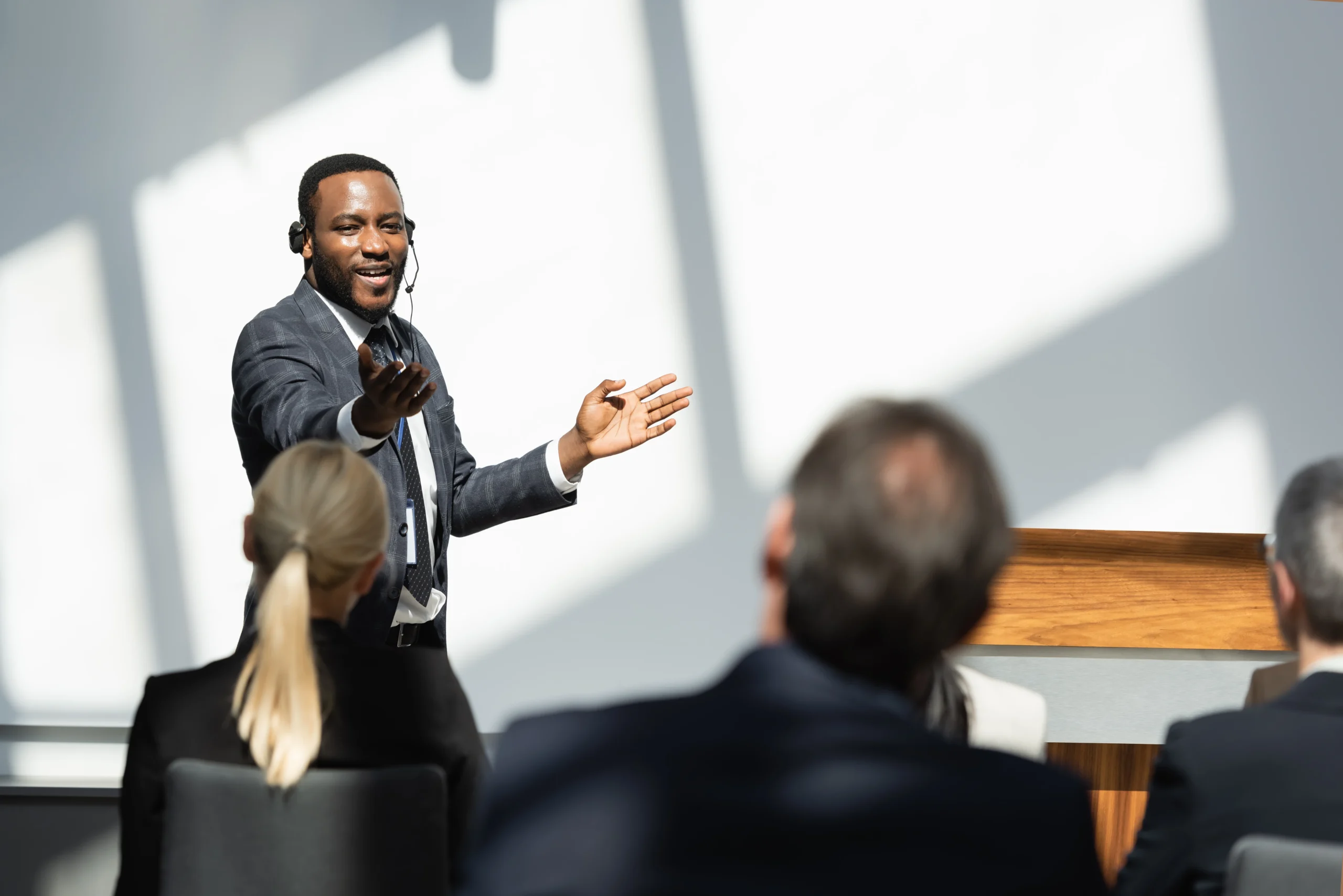 pleased african american lecturer pointing with hand during seminar with business people